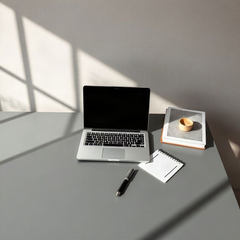 Mesa minimalista em tom ardósia com laptop aberto e nota escrita à mão